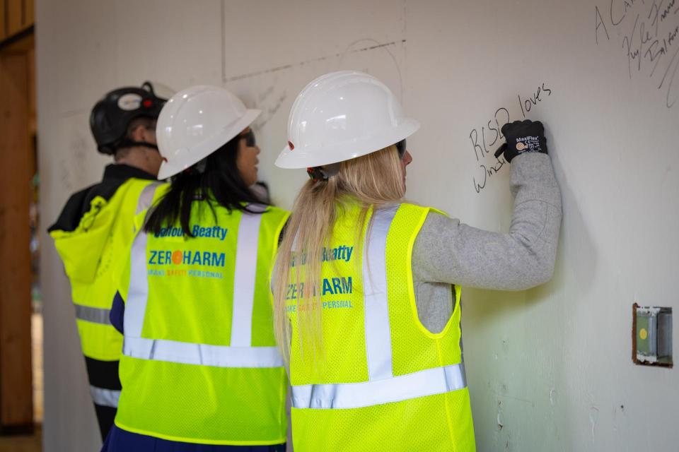 Three people signing an interior wall of a building under construction