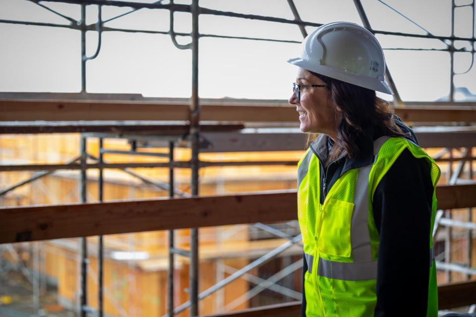 Woman in construction gear looking down at view from second floor of a building under construction