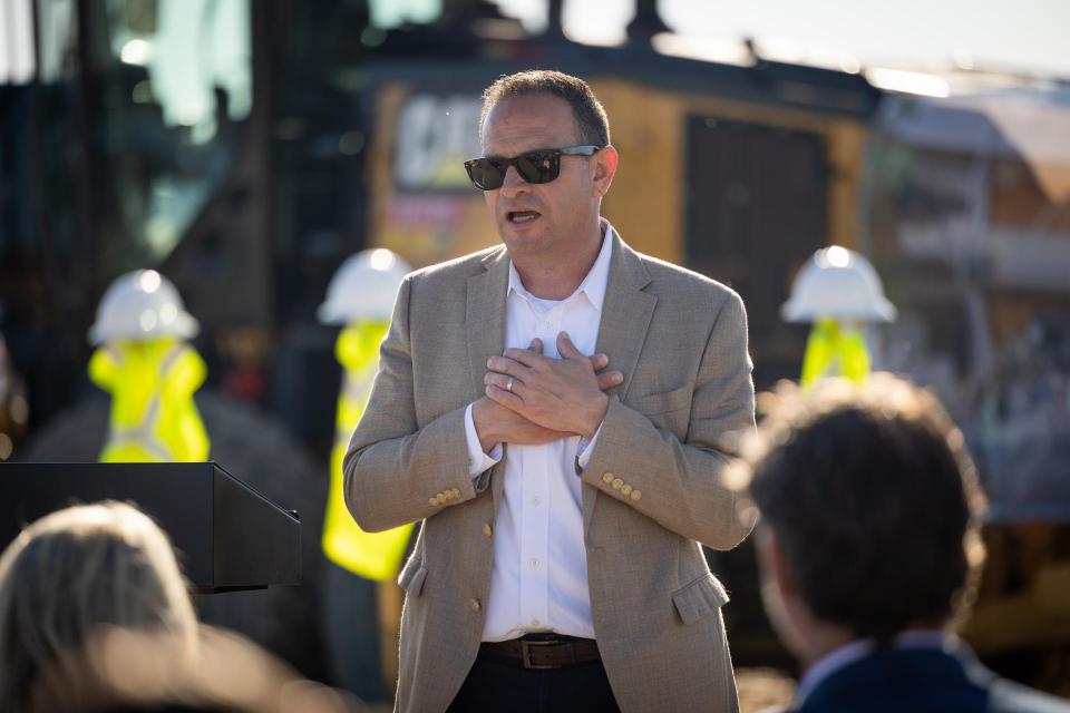 Superintendent Derk Garcia speaking to a crowd. Behind him is a construction site.